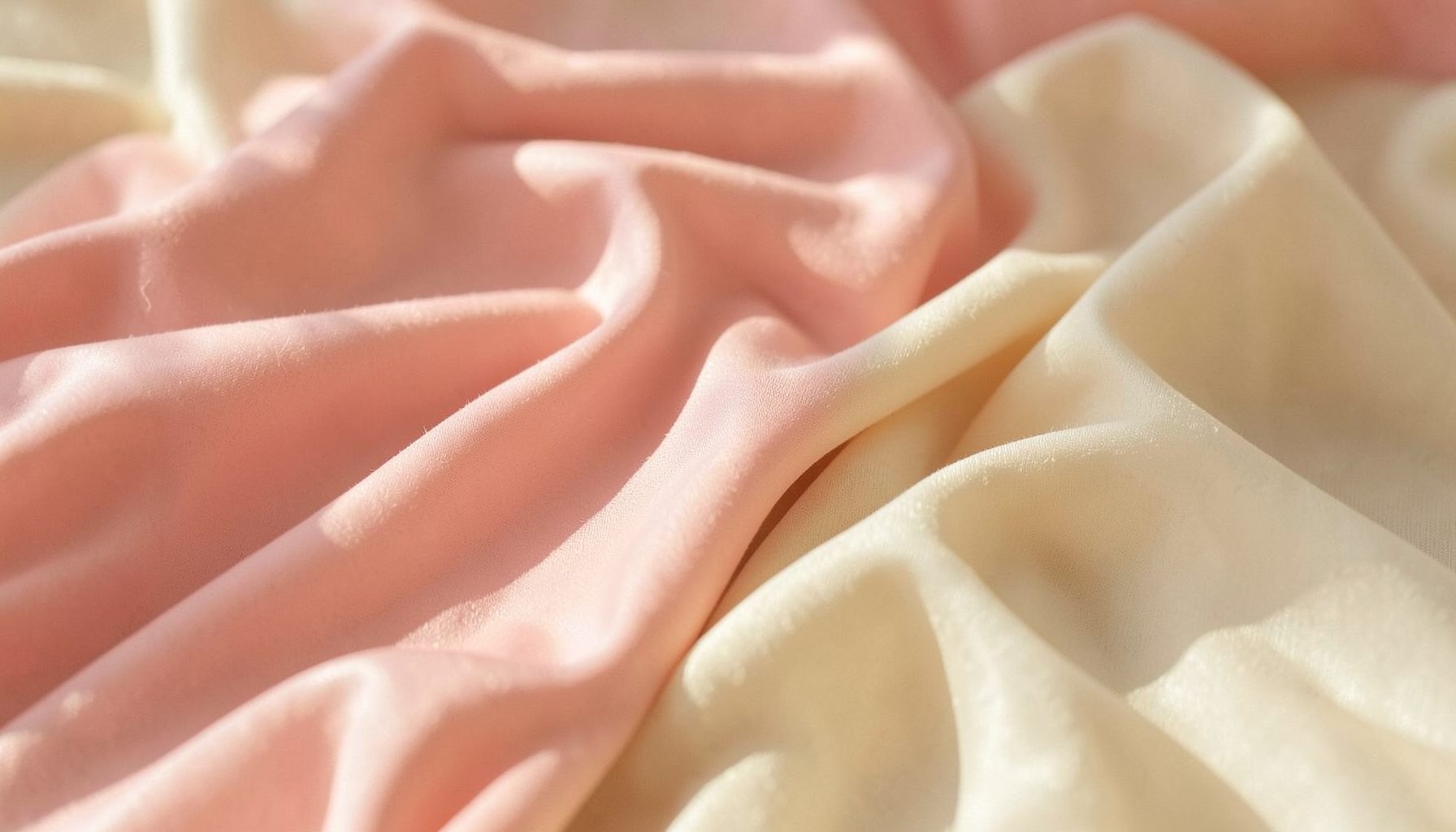 Weiche pastellrosa und cremefarbene Textilien, sanft drapiert, mit warmem natürlichem Licht
